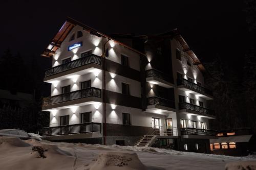 um edifício com luzes acesas na neve à noite em Vila Edelweiss em Predeal