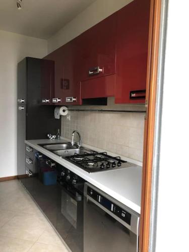 a kitchen with a stove and a sink and red cabinets at Appartamento residenziale con posto auto privato in Sassari