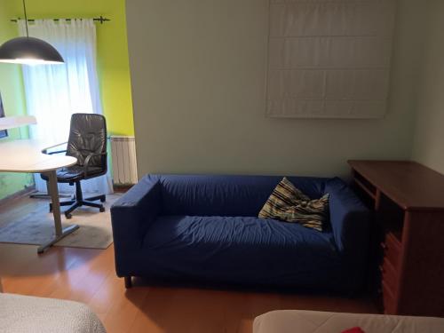 a living room with a blue couch and a desk at Global Guest Rooms in Sintra