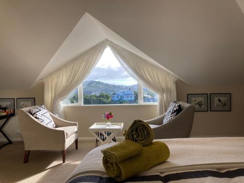 a bedroom with a bed and two chairs and a large window at Khandallah Harbour View BnB in Wellington