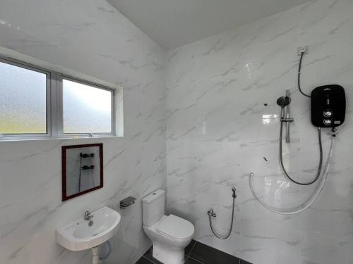 La salle de bains blanche est pourvue d'une douche et de toilettes. dans l'établissement Sunny Lake House, à Behrang Hulu