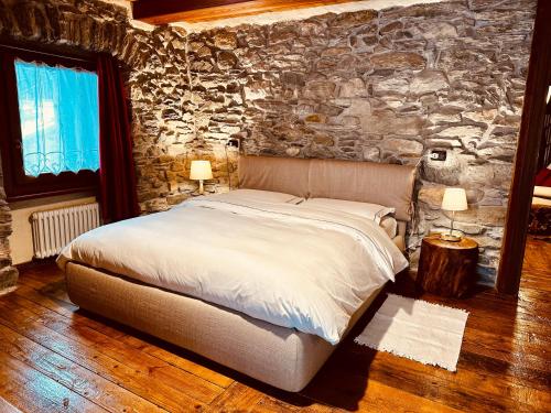 a bedroom with a bed and a stone wall at Maison Bovet in La Salle