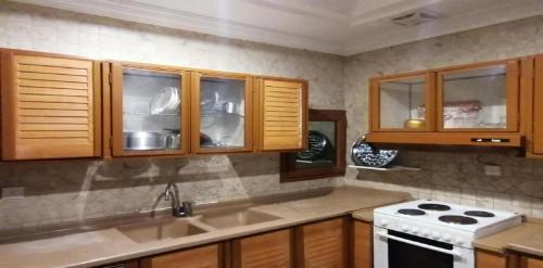 kuchnia z drewnianymi szafkami i białą kuchenką w obiekcie حياة ريف للوحدات السكنية المفروشة w mieście Dżudda