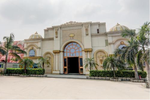 un grand bâtiment avec des palmiers devant lui dans l'établissement OYO Hotel Umrao, à Patna