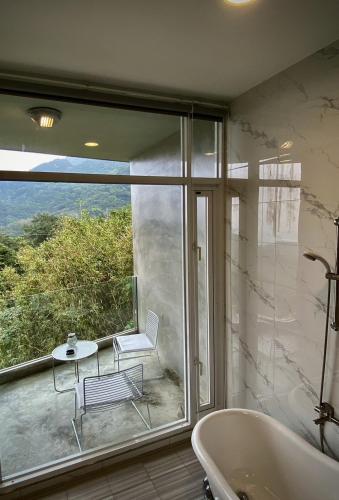 a bathroom with a tub and a table and a chair at Sunny Room in Jiufen