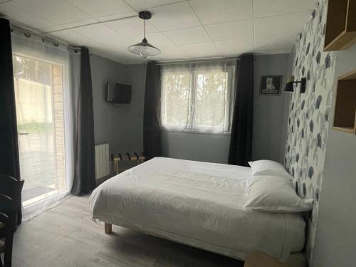 a bedroom with a white bed and two windows at Cabane du Circuit in Le Mans