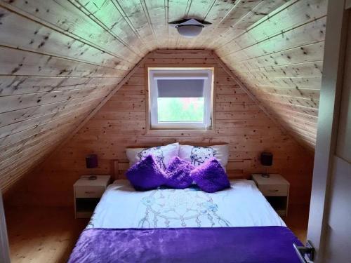 a bedroom with a purple bed in a wooden attic at Lawendowy Domek Mazury in Rydzewo