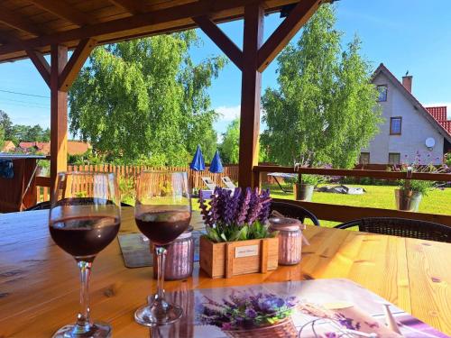 two glasses of wine sitting on a wooden table at Lawendowy Domek Mazury in Rydzewo