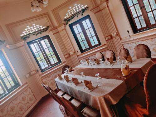 a room with a long table with chairs and windows at Grand Colonial Viveka in Kurunegala
