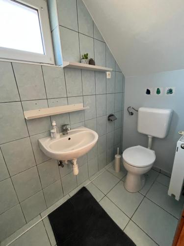 uma casa de banho com um lavatório e um WC em Luca Vendégház em Sárvár