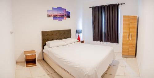 a bedroom with a white bed and a window at Rental Palhoça- Acomodações Residenciais in Palhoça