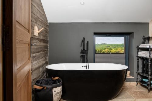 uma banheira preta numa casa de banho com uma janela em Domaine Villoire em Cassagnes