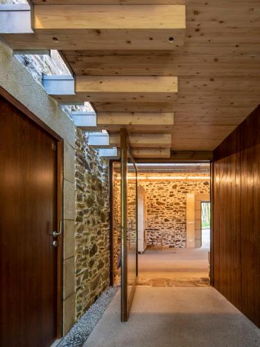 a hallway with a wooden door and a stone wall at Abeiro da loba in Madelos