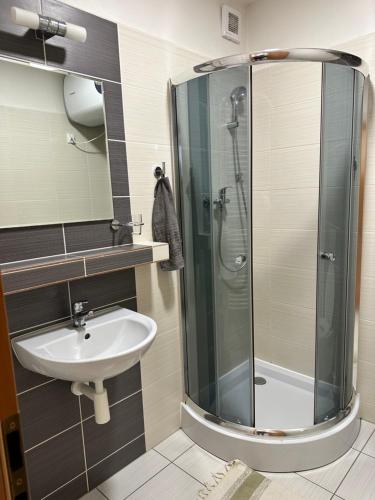a bathroom with a glass shower and a sink at Apartman pri vleku in Telgárt