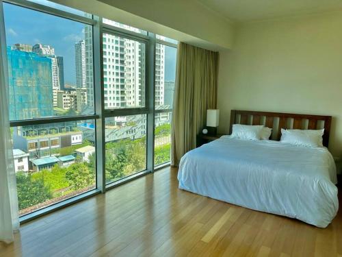 a bedroom with a large bed and large windows at Colombo Emperor Residencies in Colombo