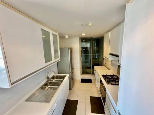 a kitchen with white cabinets and a sink and a stove at Colombo Emperor Residencies in Colombo