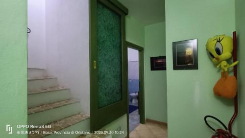 a hallway with green walls and a door with a mirror at Casa Allende in Bosa