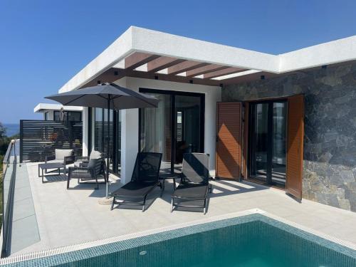 a patio with chairs and an umbrella next to a pool at Luxury Villa Lorcrimar in Masline