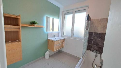 baño con bañera, lavabo y ventana en Appartement 3 étoiles de 63m2, en Cabourg