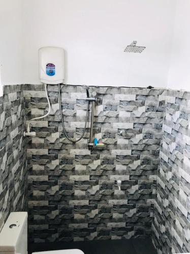 a bathroom with a stone wall with a shower at Villa Ocean Breeze in Ahangama
