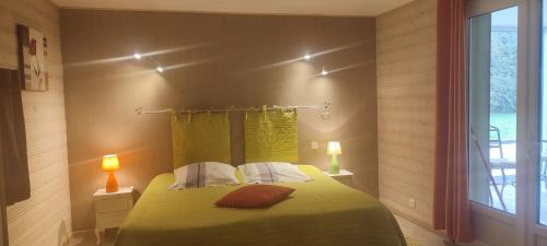 a bedroom with a green bed with two lamps and a window at Gîte cosy, sur jardin, terrasse privée, parking au calme en rdc in Gémozac
