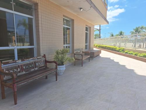 two benches sitting on a patio with a building at Aqui é pé na areia in Santos