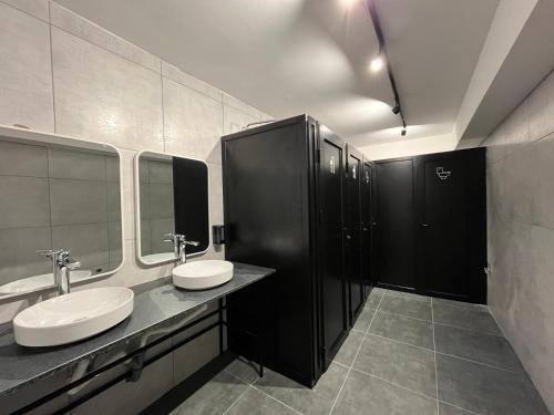 a bathroom with two sinks and a stall with mirrors at Mickitos Urban Hostel in Skopje