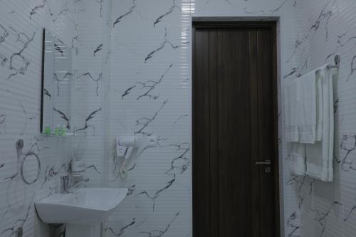 ein weißes Badezimmer mit einem Waschbecken und einem Spiegel in der Unterkunft Cobbler by Resident in Taschkent