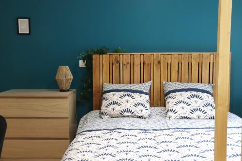 um quarto com uma cama de madeira e uma parede azul em Superbes Appartements Modernes et Neufs em Bagnols-sur-Cèze