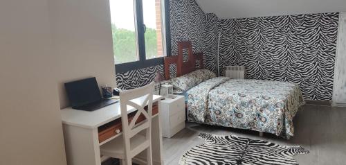 um quarto com uma cama e uma secretária com um computador portátil em Alojamiento 90 m2 em Meco