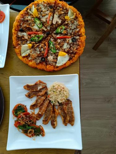 a pizza and a plate of food on a table at Fenet Hawassa Hotel in Āwasa