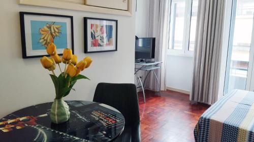 um quarto com uma mesa com um vaso de flores em Apartamento Burgo " A Preferida " no Funchal