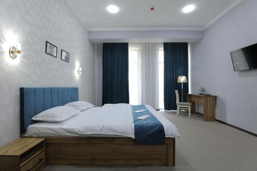 ein Schlafzimmer mit einem großen Bett und einem TV in der Unterkunft Cobbler by Resident in Taschkent