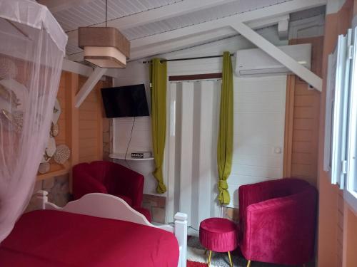 a room with two red chairs and a bed at Joli appartement in Rivière-Pilote
