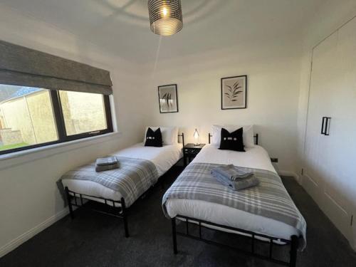 dwa łóżka w pokoju z dwoma oknami w obiekcie Coll Farm House w mieście Back