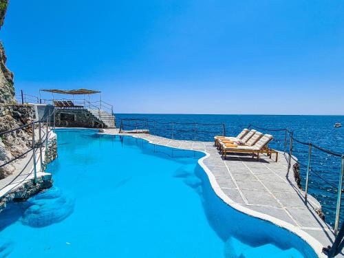 a swimming pool next to the ocean with a chair at Villa Costa degli Dei in Furore