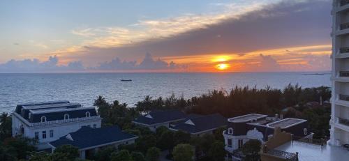 einen Sonnenuntergang über dem Wasser mit Häusern und Gebäuden in der Unterkunft HAYA Sea View Hotel Phu Quoc in Phu Quoc