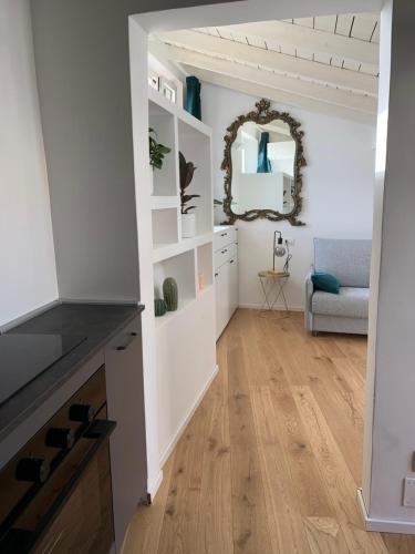 een woonkamer met witte muren, houten vloeren en een spiegel bij Via Pia 29-7 in Savona