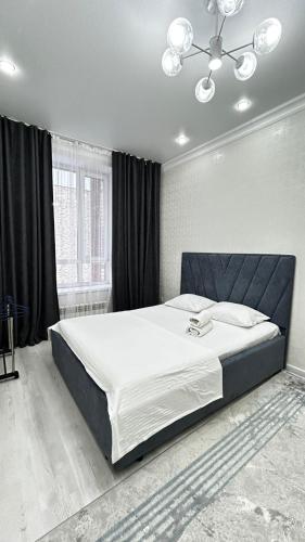 a bedroom with a large bed with a black headboard at Посуточная квартира! Аркада 37 in Taldykolʼ