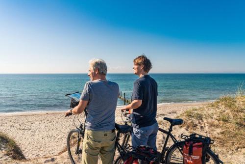 two men standing on the beach with their bikes at Luxus Ferienwohnung in Scharbeutz mit Garten in Scharbeutz