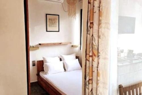 a bedroom with a bed with white pillows and a window at Bungalow Ramena beach Antsiranana in Andjamen