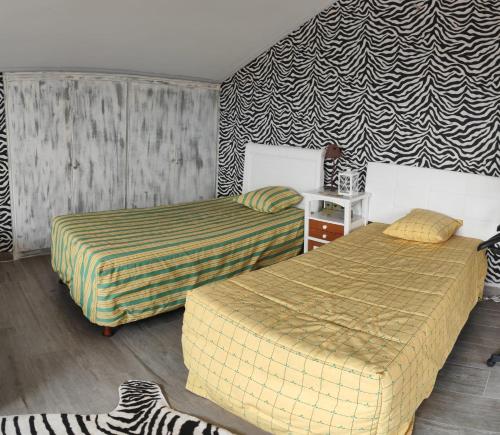 a bedroom with two beds and a zebra patterned wall at Alojamiento independiente dentro de chalet 3er piso in Meco