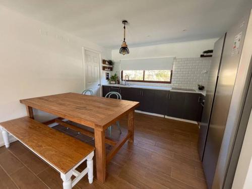 cocina con mesa de madera y nevera en Acogedora casa al borde del Río Pingueral, en Dichato