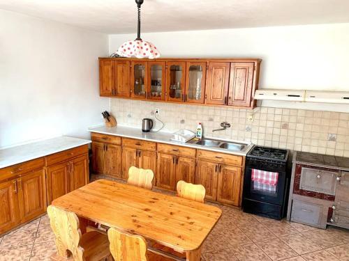 eine Küche mit Holzschränken und einem Holztisch in der Unterkunft Penzión Heľpa (do 25 hostí) in Heľpa