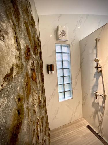 a bathroom with a shower and a stone wall at Sunny Room in Jiufen