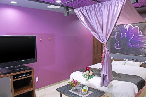 Dormitorio púrpura con cama y TV en パルアネックス鹿島店 en Ureshino
