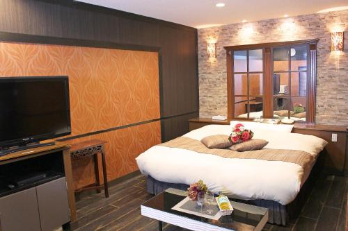 Habitación de hotel con cama grande y TV de pantalla plana. en パルアネックス鹿島店 en Ureshino