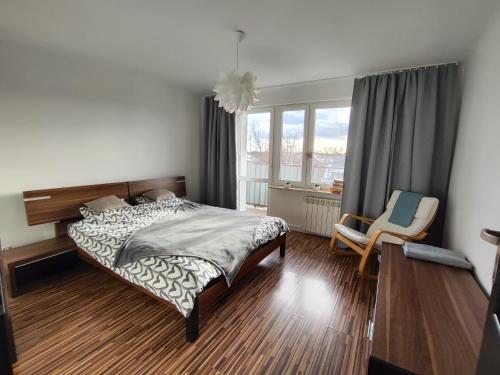 a bedroom with a bed and a chair and a window at Apartament w centrum in Włodawa