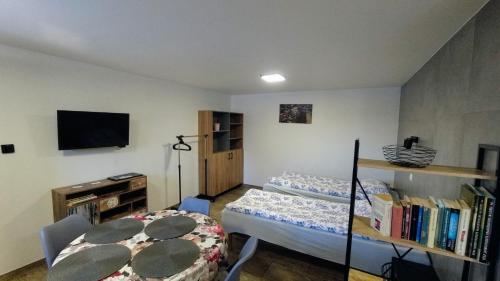 a room with two beds and a tv and a table at Przystanek Tykocin - apartamenty gościnne in Tykocin