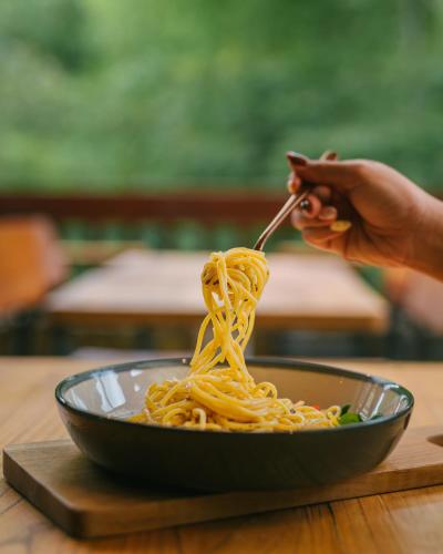 a person eating a bowl of noodles with a fork at Glamping tent in Pelaga Eco Park in Patjung